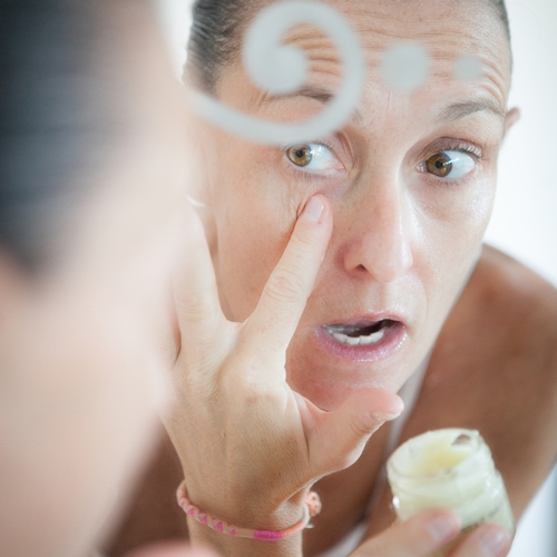 Visage de femme dans un miroir en train de mettre du beurre de karité sur sa peau